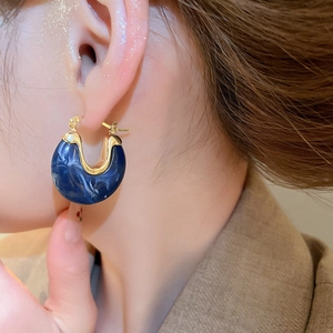 Gros plan de boucles d'oreilles en résine marbrée bleu marine et accents en métal doré
