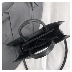 Detailed top view of black leather tote bag with multi-compartment interior and zip pocket