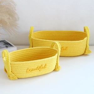 Detail of two yellow woven cotton rope baskets with beautiful embroidery and tassels