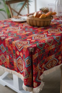 Close-up of red ethnic jacquard tablecloth with geometric patterns and beige tassels