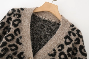 Détail du cardigan léopard en maille col V avec bouton doré sur cintre bois
