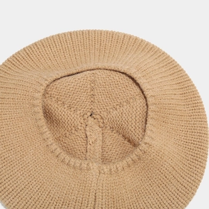 Detailed close-up of light khaki cable knit texture on a warm winter beret hat