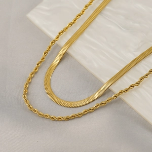 Golden double-layer necklace set with minimalist twist and snake chain on marble
