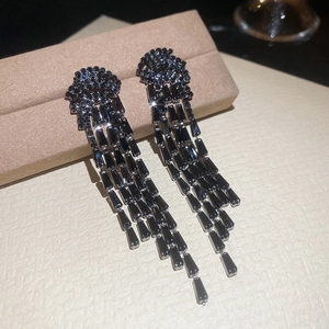 Détail de boucles d'oreilles à longs pompons noirs avec cristaux de zircon sur présentoir