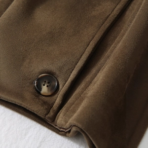 Gros plan d'un trench en daim marron avec boutons en écaille et coutures détaillées
