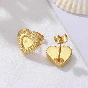 Elegant gold heart stud earrings set on a white shell prop, showing front and back details