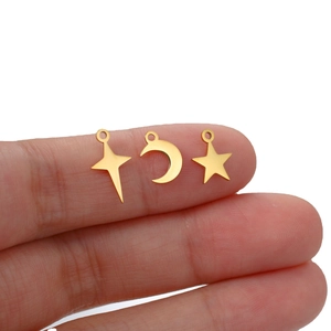 Polished stainless steel star and moon charms held by hand for jewelry making
