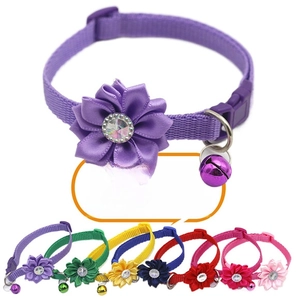 Close-up of colorful pet collars featuring satin flowers, rhinestones, and metal bells