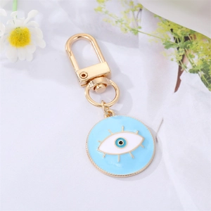 Détail du charm œil maléfique en émail bleu avec porte-clés doré sur fleurs