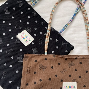Detail of corduroy tote bags with sweet candy patterns and colorful braided handles