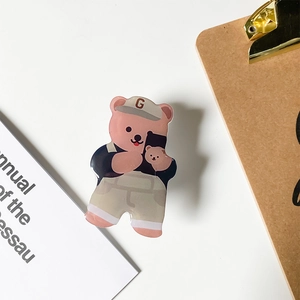 Detail of pink cartoon bear acrylic phone stand with a baseball cap on a desk background