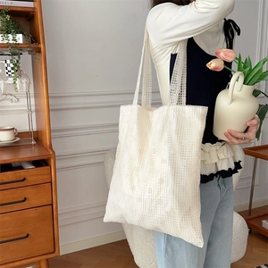 Close-up of a white lace tote bag featuring intricate 3D floral embroidery and mesh texture