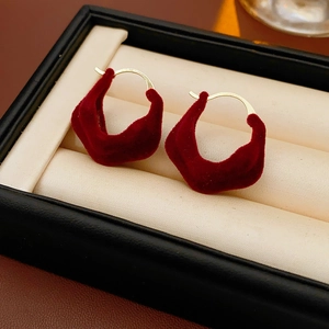 Close-up of red velvet irregular round earrings in a black and beige jewelry box