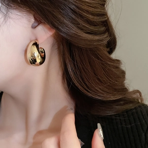Gros plan d'un mannequin portant des boucles d'oreilles en métal doré en forme de goutte