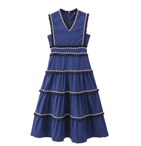 Détail de la robe bleu foncé à col en V avec jupe à volants et franges géométriques noires