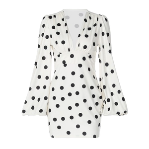 Dettaglio dell'abito bianco a pois con scollo a V profondo e maniche a palloncino