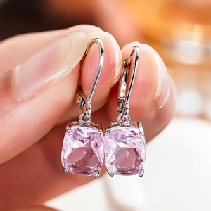 Detail of hand-held silver drop earrings with cushion-cut pink sapphire zirconia