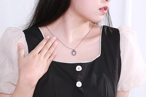 Close-up of elegant silver stainless steel necklace with a diamond oval pendant on neck