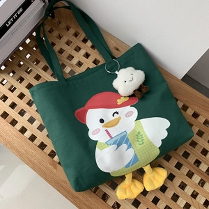 Close-up of green canvas tote bag with cartoon duck print and plush yellow webbed feet