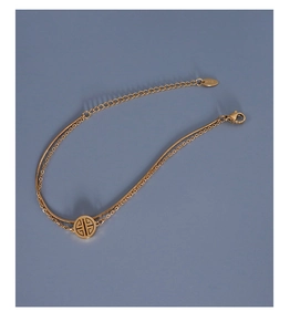 Close-up of 18k gold-plated double-layer snake chain bracelet with round hollow pendant
