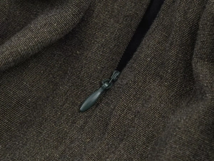 Detail of dark brown coarse knit fabric texture and matching invisible drop zipper