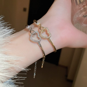 Elegant gold and silver heart-shaped zircon bangles with adjustable chain on a model wrist