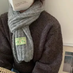 Detailed texture of light gray knitted wool scarf with highland virgin wool woven label