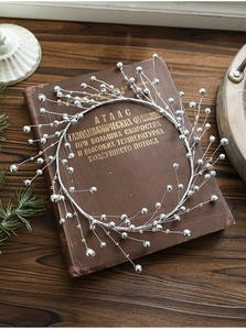Detailed view of silver beaded vintage wreath decoration on a retro rustic book