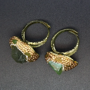 Macro detail of vintage gold open ring with green raw stone and amber rhinestones