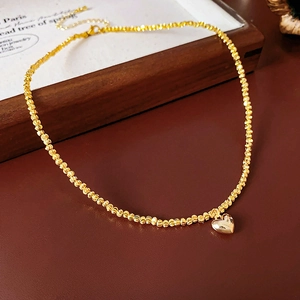 Detailed view of a gold heart pendant necklace crafted with delicate beads on dark background
