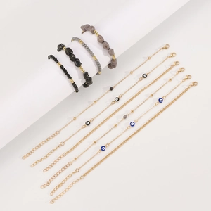 Detalle de cadenas bohemias doradas y cuentas de piedra con ojo turco en soporte blanco