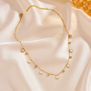 Collier élégant en titane doré avec disques de nacre et cristaux sur fond de satin