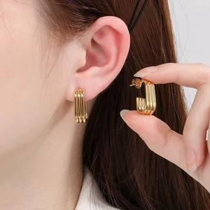 Three-line ribbed U-shaped earrings in 18K gold plated stainless steel on model