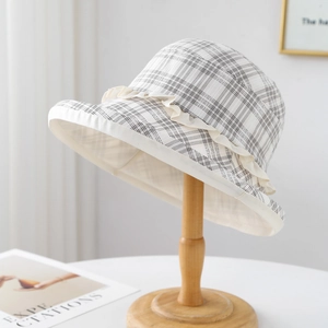 Chic beige plaid bucket hat with lace trim on a minimalist wooden stand for women