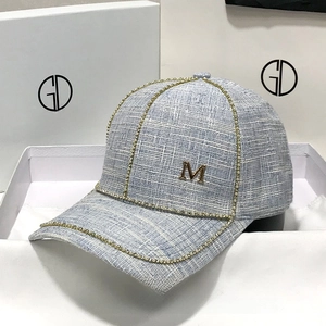 Light blue tweed baseball cap with pearl rhinestones and gold M letter in a gift box