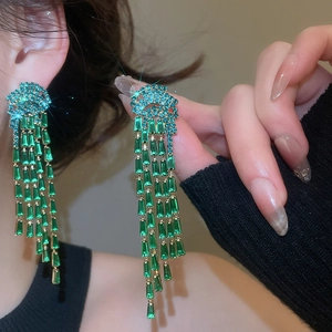 Close-up detail of luxury emerald green zircon flower tassel earrings with sparkles