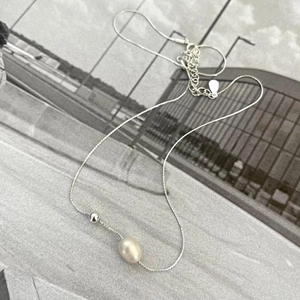 Detail of 925 sterling silver necklace with pearl and silver bead on magazine background