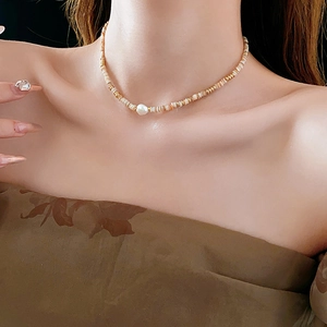 Detail of 14K gold-plated beaded necklace featuring a white baroque pearl on collarbone