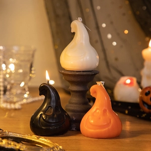 Detailed close-up of ghost-shaped Halloween candles in black, white and orange wax