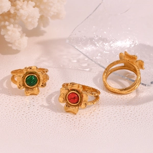 Detailed view of three 18K gold plated flower rings with green and red stones on white backdrop