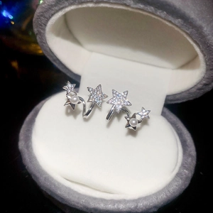 Gros plan de boucles d'oreilles étoiles argentées avec perles et zircon dans un écrin gris