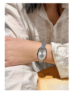 Detailed shot of an oval silver quartz watch with a vintage metal chain strap on wrist