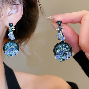 Dettaglio di orecchini a fiore con strass blu e finitura in smalto nero elegante