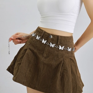 Detail view of silver butterfly link chain belt worn over a pleated skirt