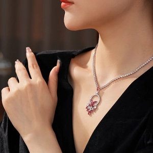 Close-up of model wearing silver butterfly necklace with red crystals on black dress