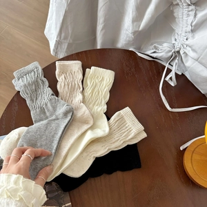 Calze slouch da donna in cotone a maglia in colori neutri su tavolo di legno