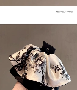 Detail of floral satin hair claw with black flower print and elegant pearl pendant