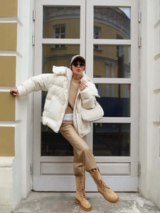 Detailed view of white hooded winter jacket with large flap pockets and quilted texture