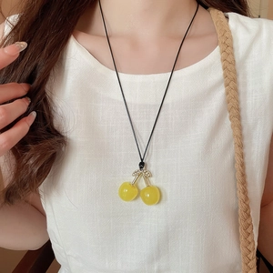 Detail of yellow cherry pendant necklace with gold stem and crystals on model