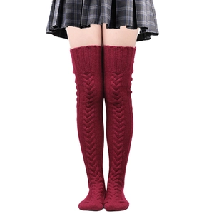 Detail of red cable-knit over-the-knee socks with textured pattern and thigh-high length